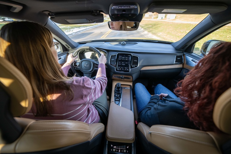 An aerial view of two women sitting in the front of a Volvo XC90 while using adaptive cruise control/