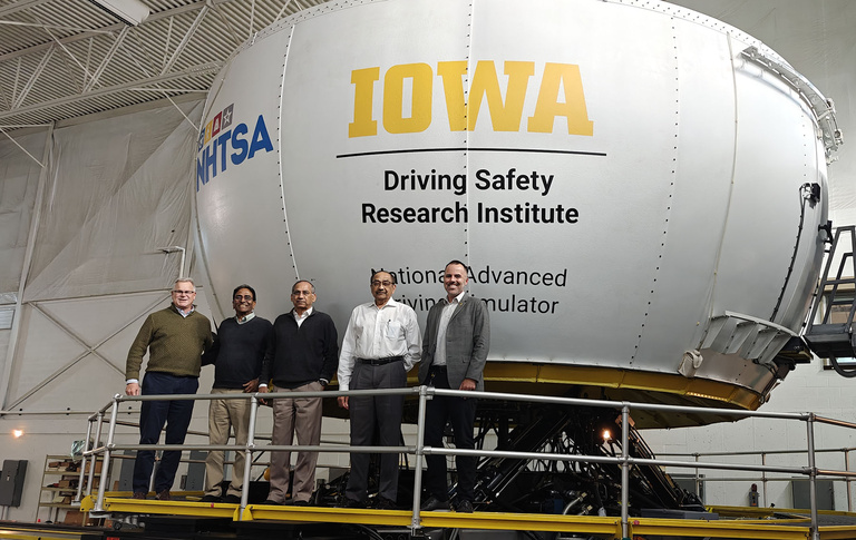 Group with Raju Dandu poses in front of the NADS-1 simulator