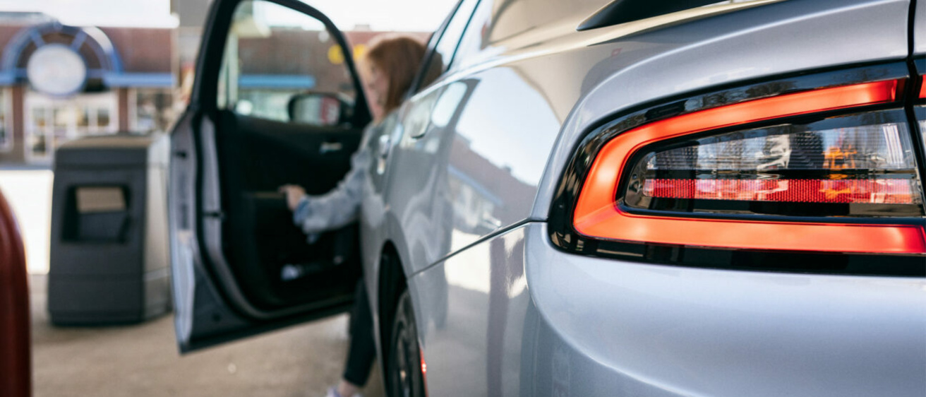 Woman stepping out of a grey car